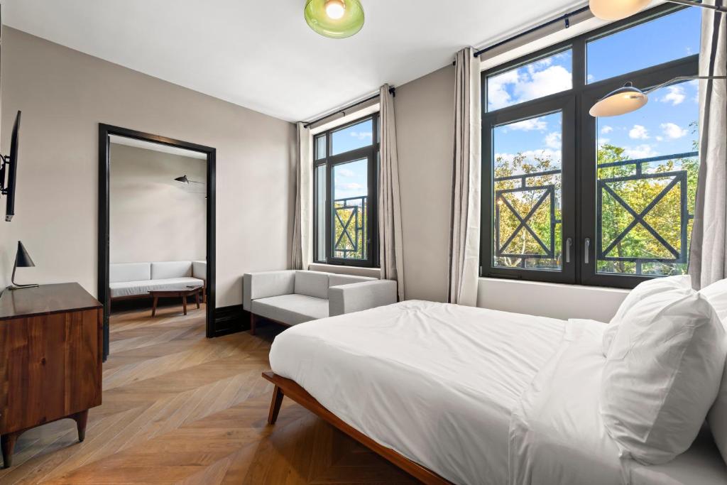 Un dormitorio con una cama y una silla y ventanas. en Freeman 303 by Rove - 1BR Condo with Shared Amenities, en Nueva York