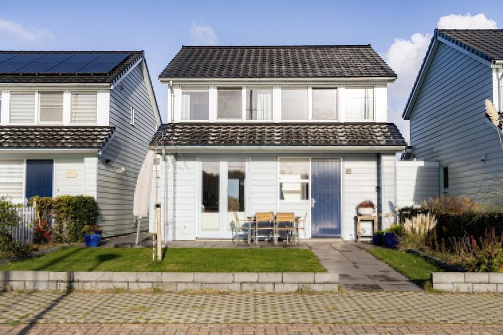 une maison blanche avec deux maisons bleues dans l'établissement Watervilla Den Oever VP066, à Wieringerwerf