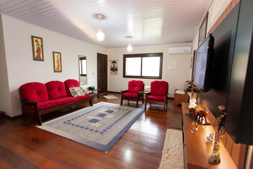 een woonkamer met rode stoelen en een flatscreen-tv bij Casa Joseph in Gramado