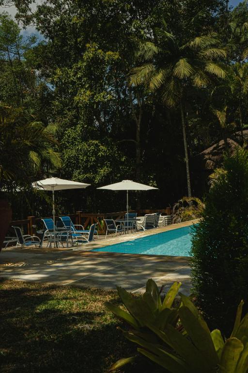 a swimming pool with lounge chairs and umbrellas at Urikana Boutique Hotel in Teresópolis
