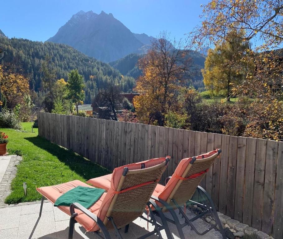 two chairs sitting on a patio with a fence at Yvonne Mayer in Scuol
