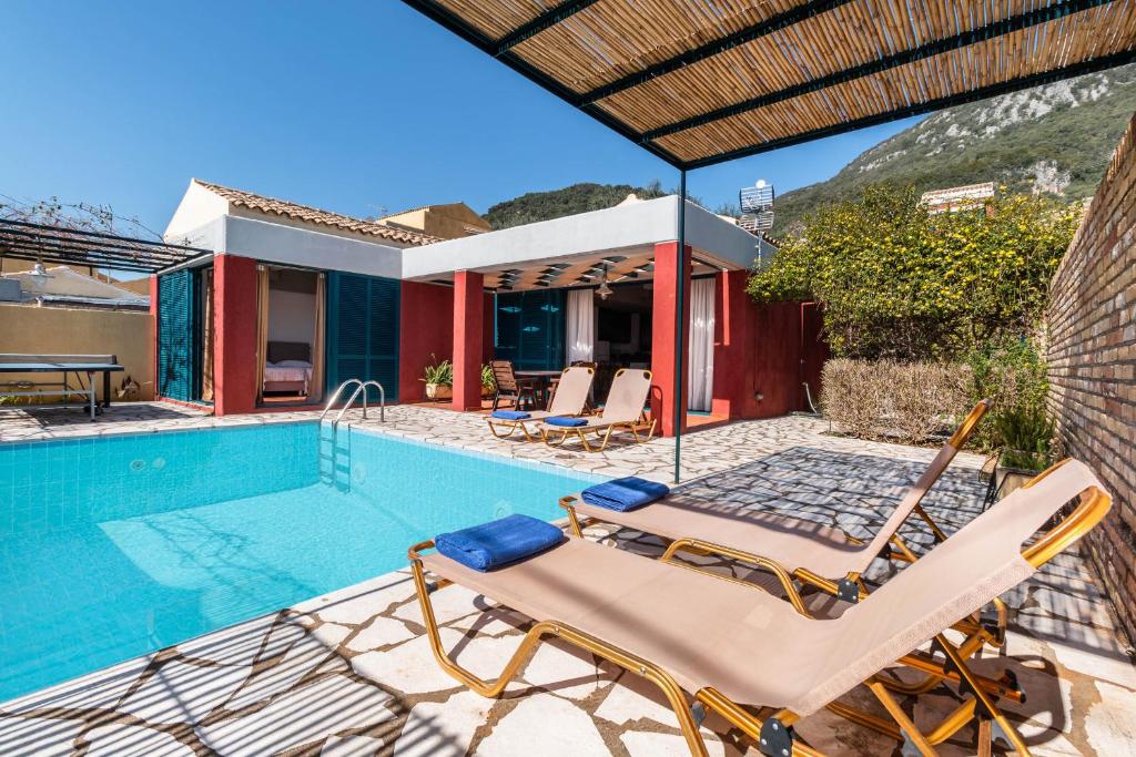 a villa with a swimming pool and two lounge chairs at Barbati Beach - Villa Lefkada in Barbati