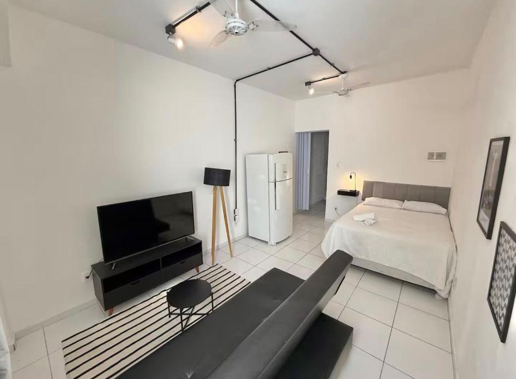 een witte slaapkamer met een bed en een televisie bij Centro - Divino apartamento in Rio de Janeiro