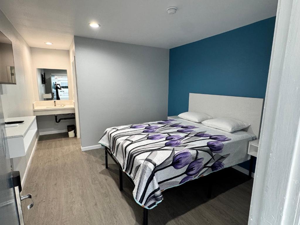 ein Schlafzimmer mit einem Bett und einer blauen Wand in der Unterkunft Angel's Motel near Anaheim in Orange