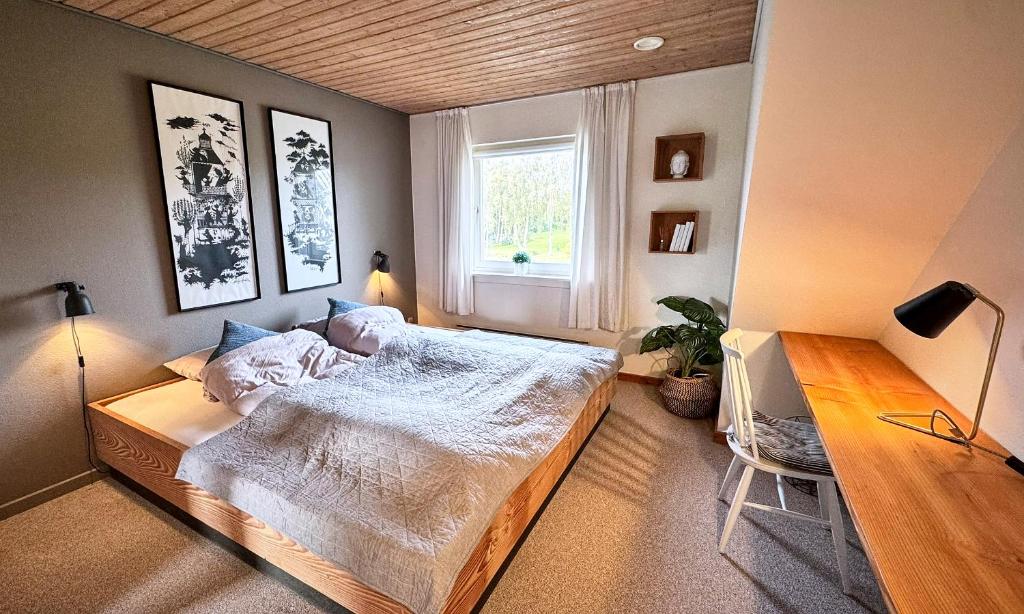 une chambre avec un grand lit et une fenêtre dans l'établissement Stylish vacation home - close to sea and nature, à Hejls
