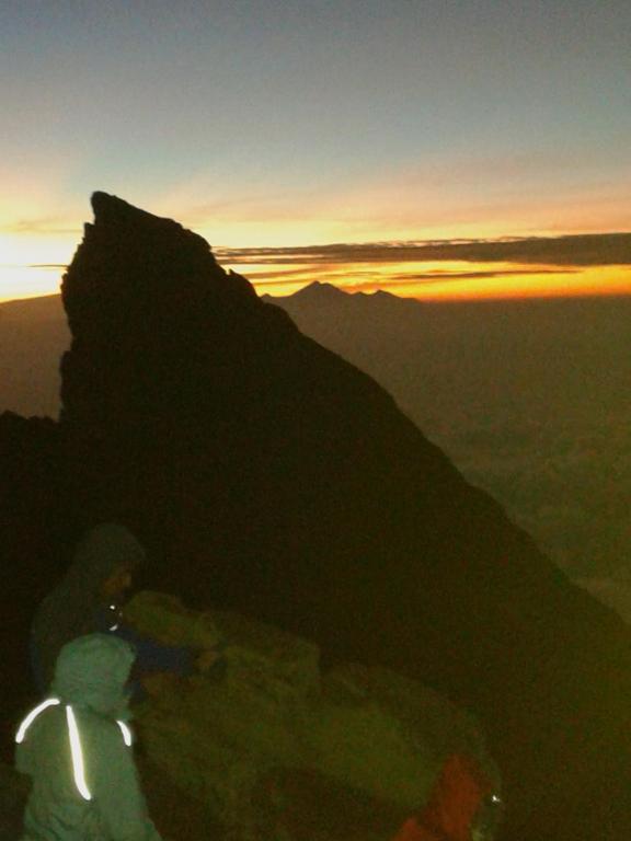 a person standing on top of a mountain at sunset at Pondok Lembah Dukuh Homestay in Tirtagangga