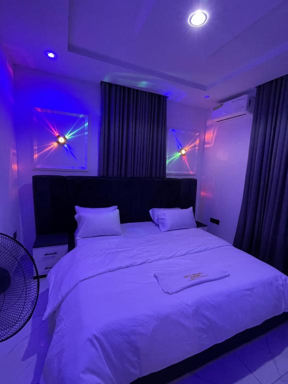 ein Schlafzimmer mit einem großen weißen Bett mit violetten Lichtern in der Unterkunft House of jessy in Iju