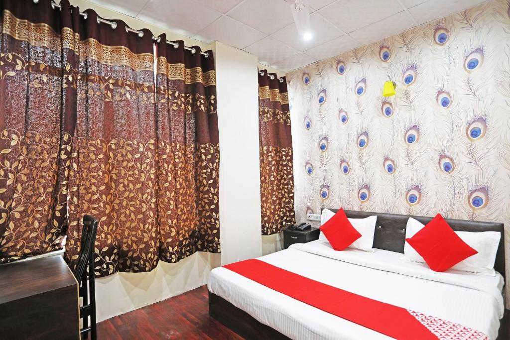 a bedroom with a bed with red pillows and curtains at Hotel O Platinum Inn in Faridabad