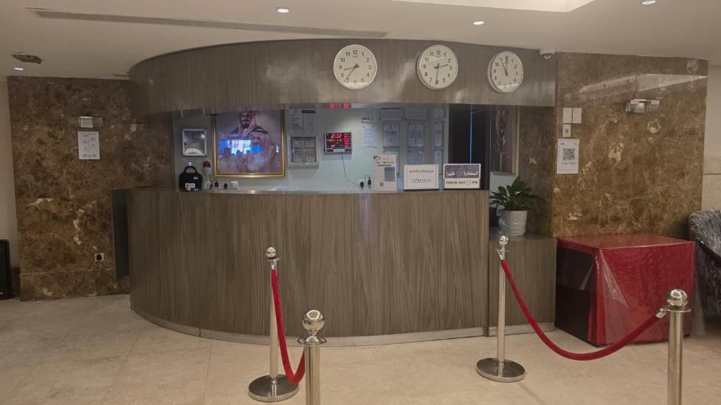a lobby with a counter with clocks on the wall at Al JAWHRA TOWER HOTEL in Mecca