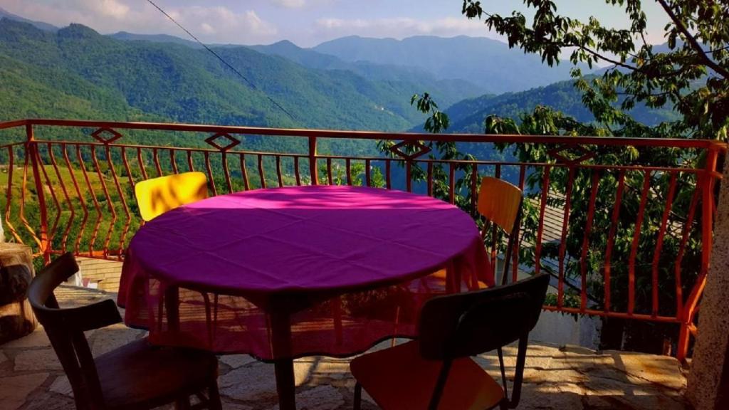 une table violette sur un balcon avec vue sur les montagnes dans l'établissement Caregli Countryhouse, à Borzonasca