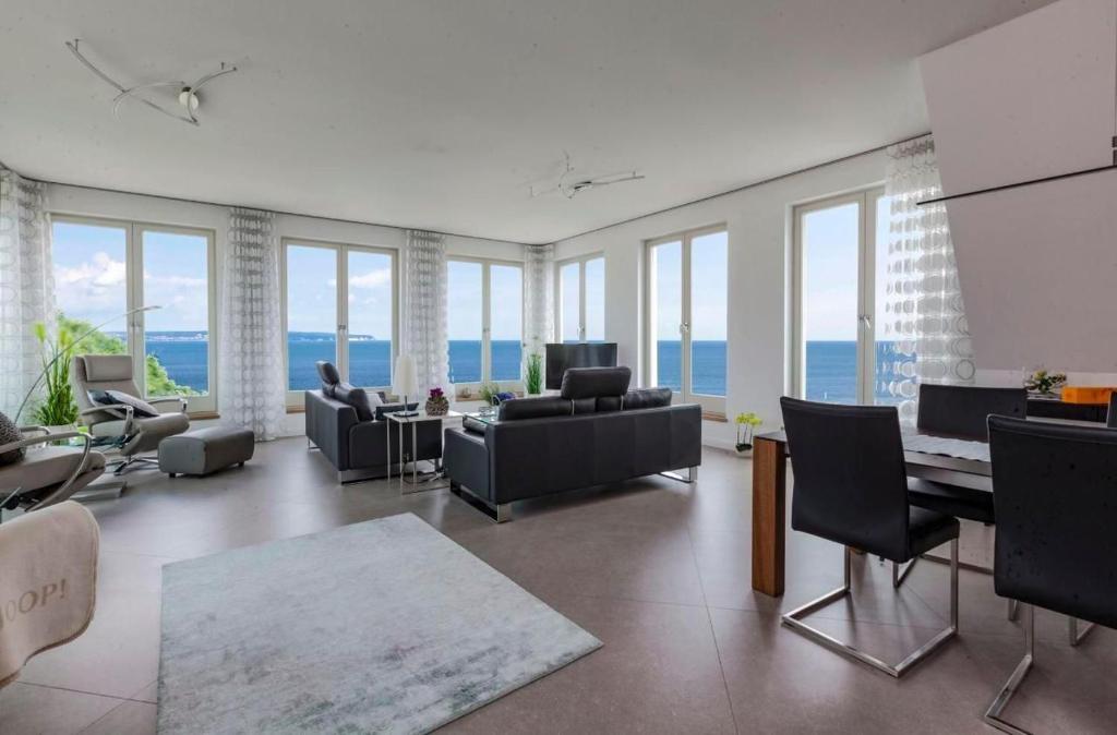 ein Wohnzimmer mit Sofas und Stühlen und Fenstern in der Unterkunft Appartement in Sellin mit Garten, Sauna und Terrasse und Meerblick in Ostseebad Sellin