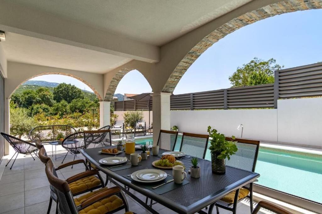 a dining room with a table and chairs and a pool at Villa Eden with heated pool in Omiš