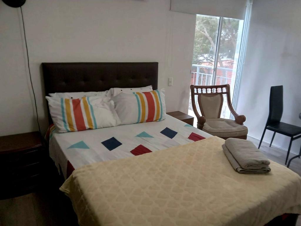 1 dormitorio con 1 cama con silla y ventana en Con Piscina, Cómodo y acogedor Apartaestudio en el rodadero, en Gaira