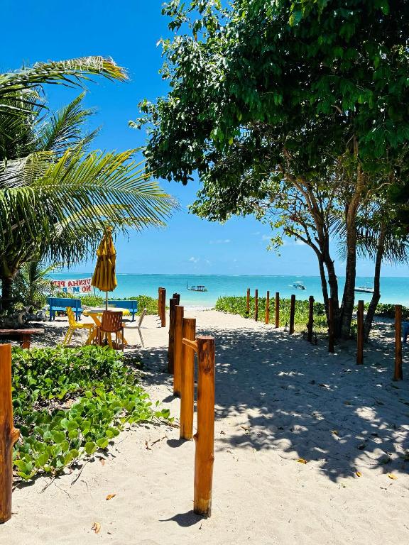 a sandy beach with a table and chairs and the ocean at Fonte dos Corais - Suíte Lua na Praia in Maragogi