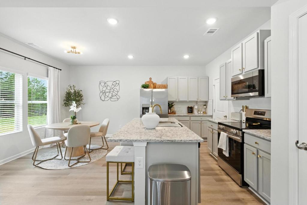 eine Küche mit weißen Schränken und einem Tisch mit Stühlen in der Unterkunft New Listing The Neutral Nook with Firepit in Athens