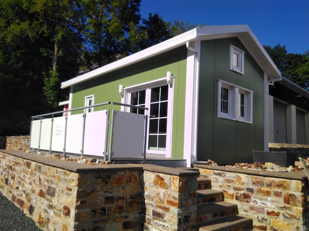 une maison verte et blanche sur un mur de pierre dans l'établissement Ferienhaus Mit Grill In Bad Marienberg, à Bad Marienberg