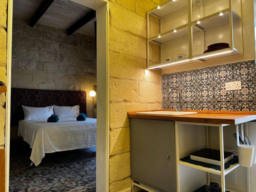 a bedroom with a bed and a kitchen with a counter at Phi Home Bormla in Birgu
