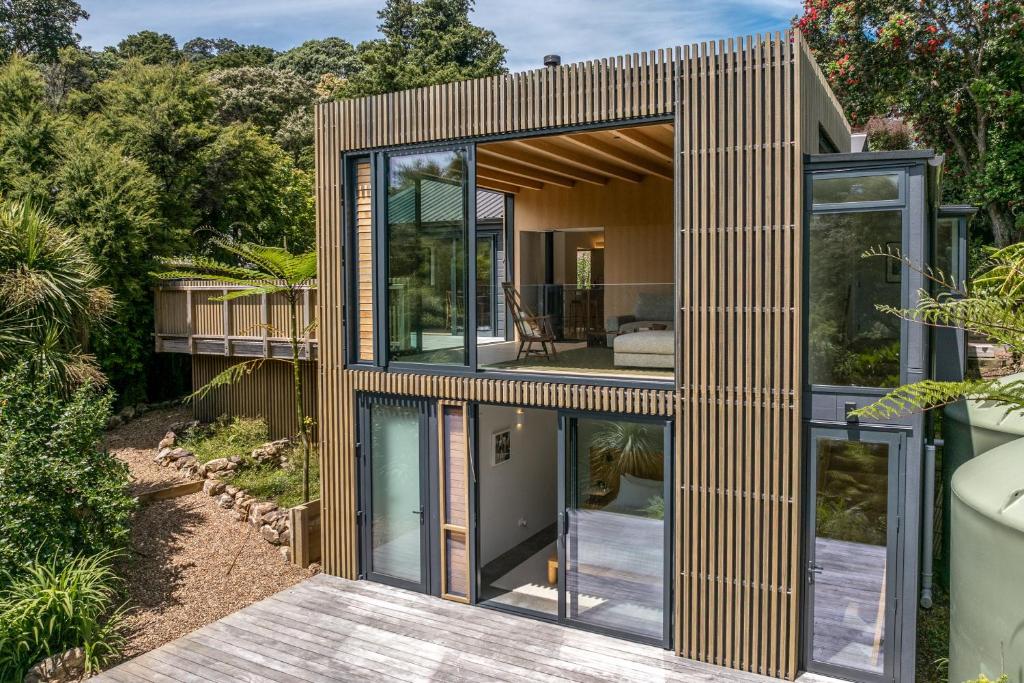 a small house with glass doors on a deck at Birdsong Sanctuary - Be My Guest Waiheke in Waiheke Island