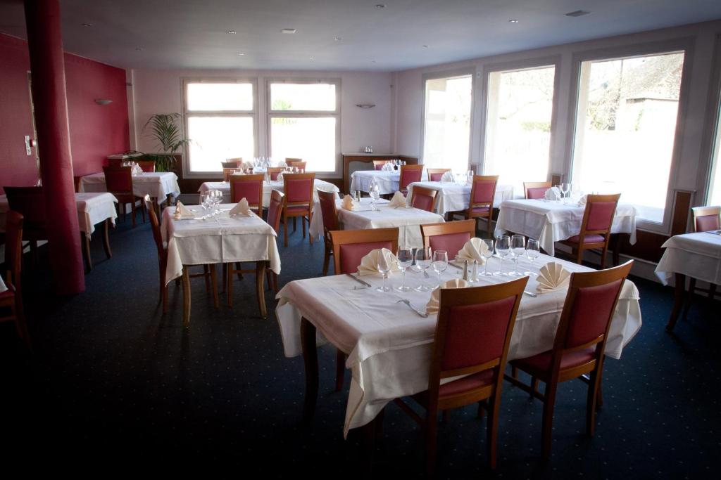 a dining room with white tables and chairs and windows at Hotel au Moyne De Saire in Réville