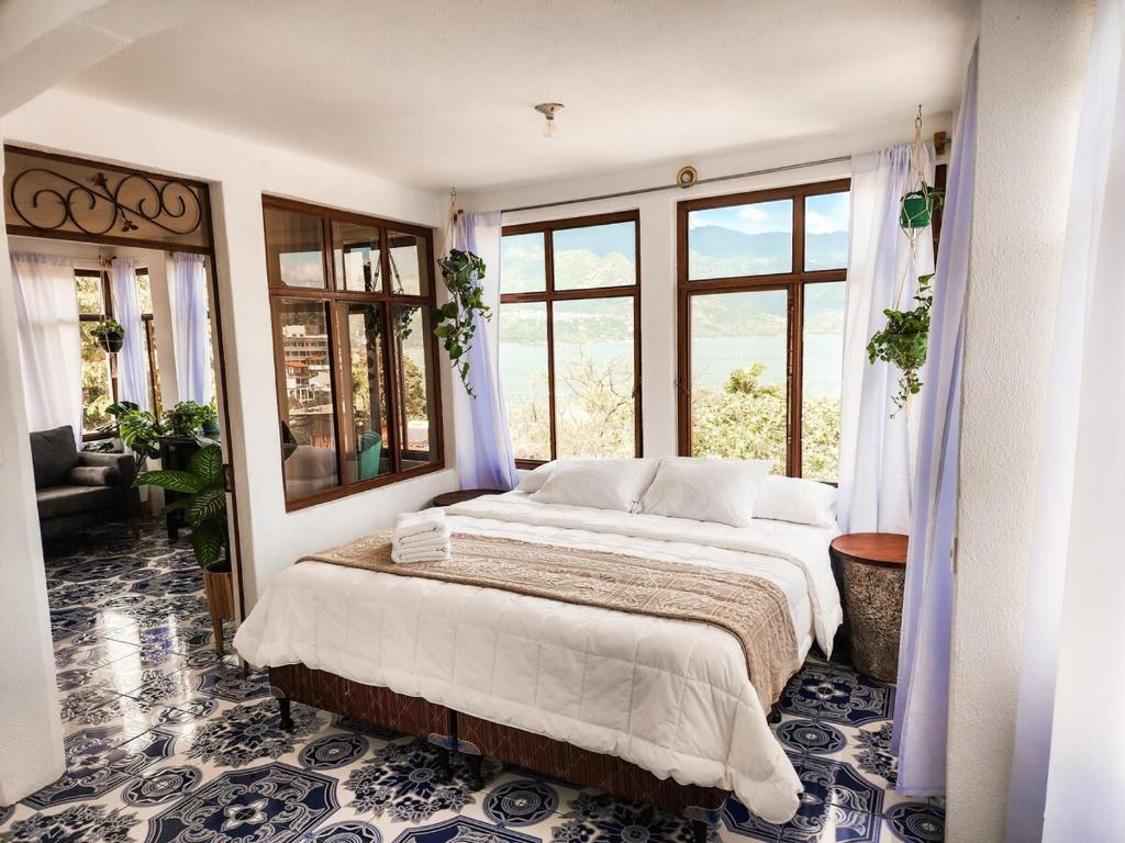 a bedroom with a large bed in a room with windows at Rare Find, Amazing View! Walk to All! in San Pedro La Laguna