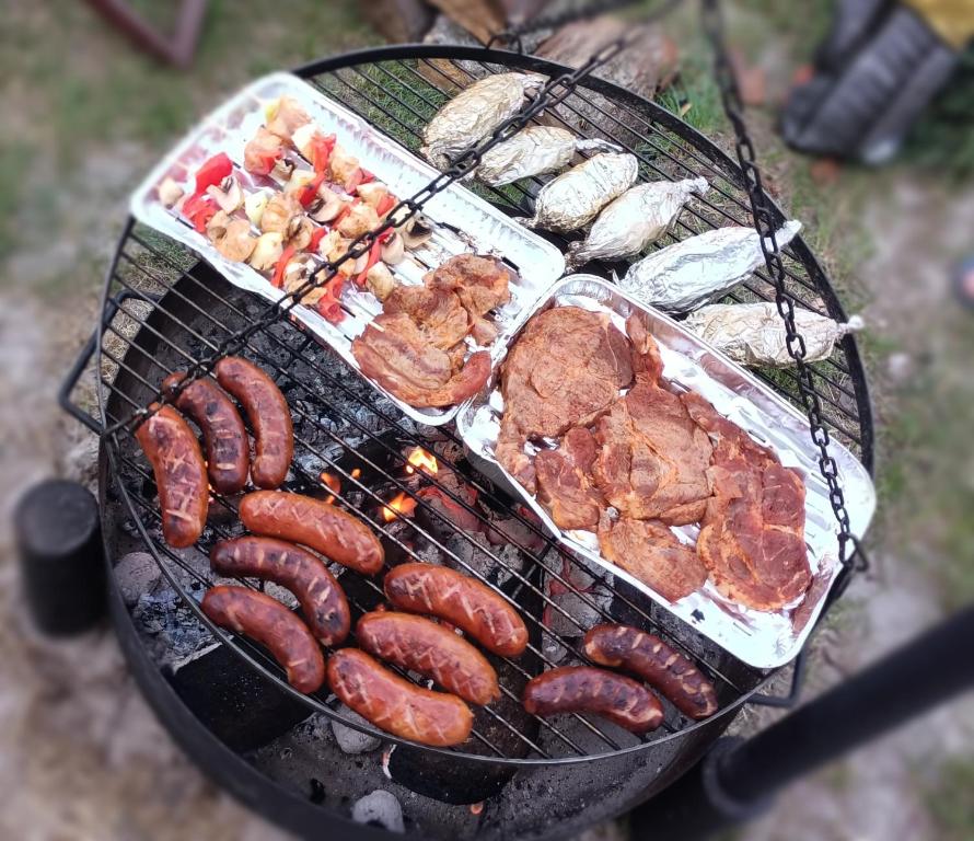 ein Grill mit Wurst und anderen Speisen drauf in der Unterkunft Leśny Domek in Piłka