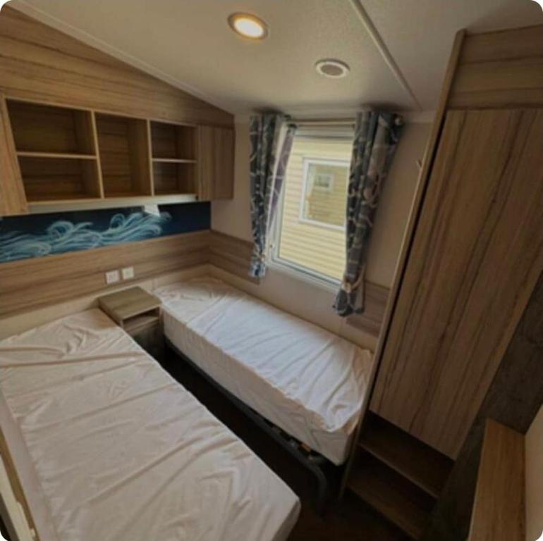 a small bedroom with two beds in a trailer at Sunrise Holidays Skegness - Pearl in Skegness