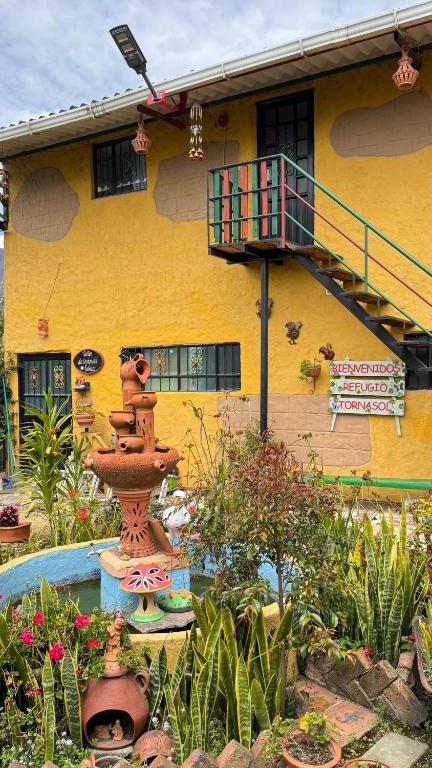 a yellow building with a flower garden in front of it at Refugio tornasol in Duitama