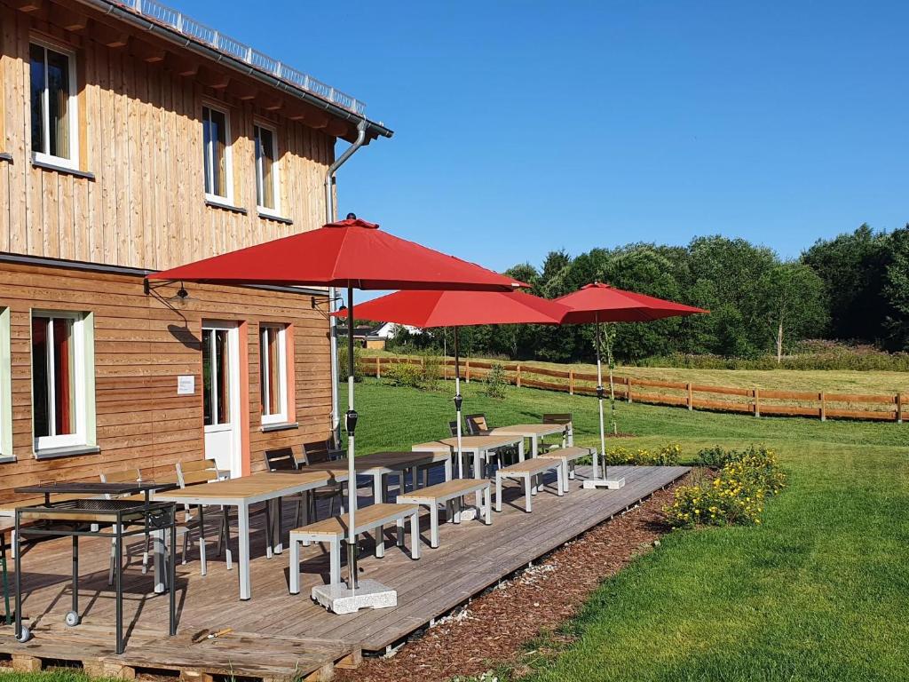 a deck with tables and umbrellas next to a building at Bergwiesenalm in Buntenbock