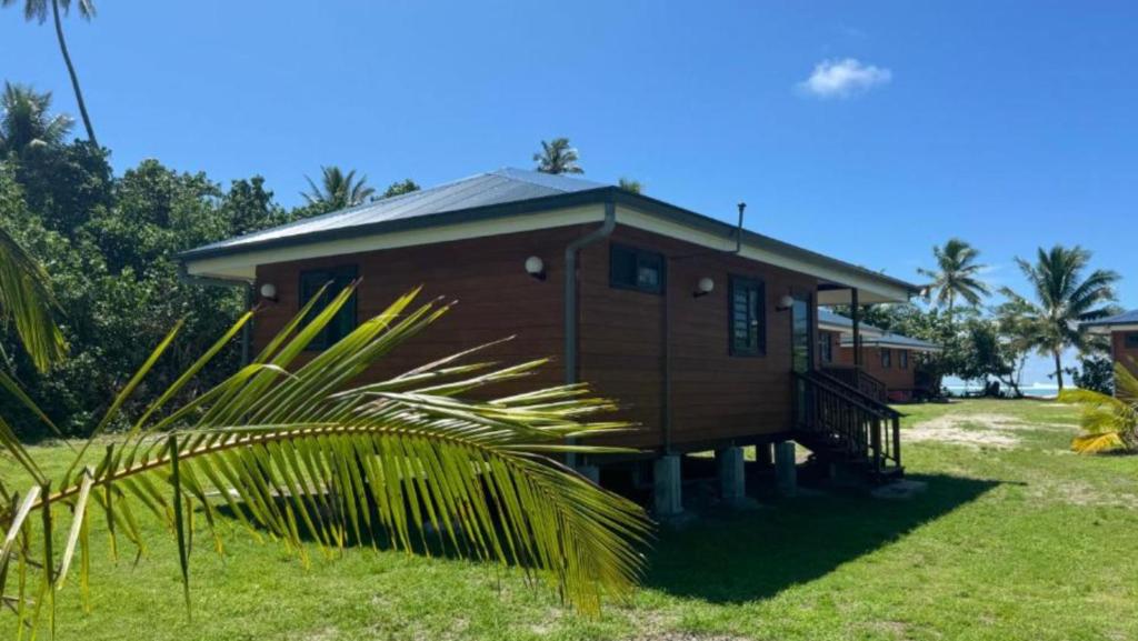 a small house with a grassy yard in front at HUAHINE- Fare Montagne in Parea
