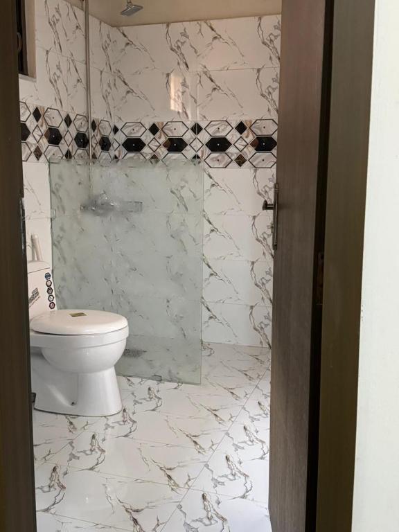 a bathroom with a toilet and a glass shower at Amberwood residency in Islamabad