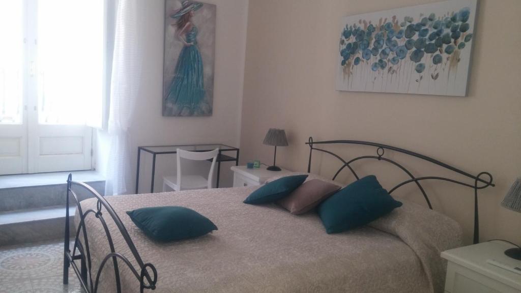 a bedroom with a bed with blue pillows on it at Casa Barnaba in Siracusa