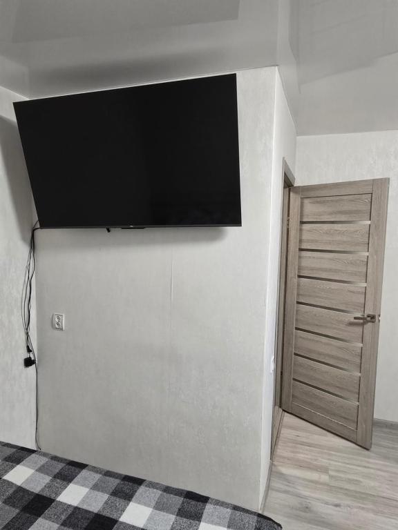 Une télévision à écran plat est installée sur un mur à côté d'une porte. dans l'établissement 1 кімнатна квартира в центрі міста, à Soumy