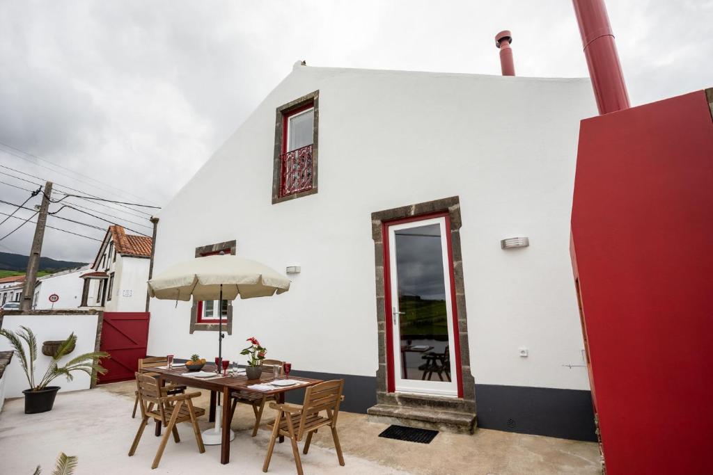 eine Terrasse mit Tisch und Stühlen und ein Gebäude in der Unterkunft Ferienhaus für 4 Personen ca 120 qm in Algarvia, Azoren Sao Miguel in Algarvia