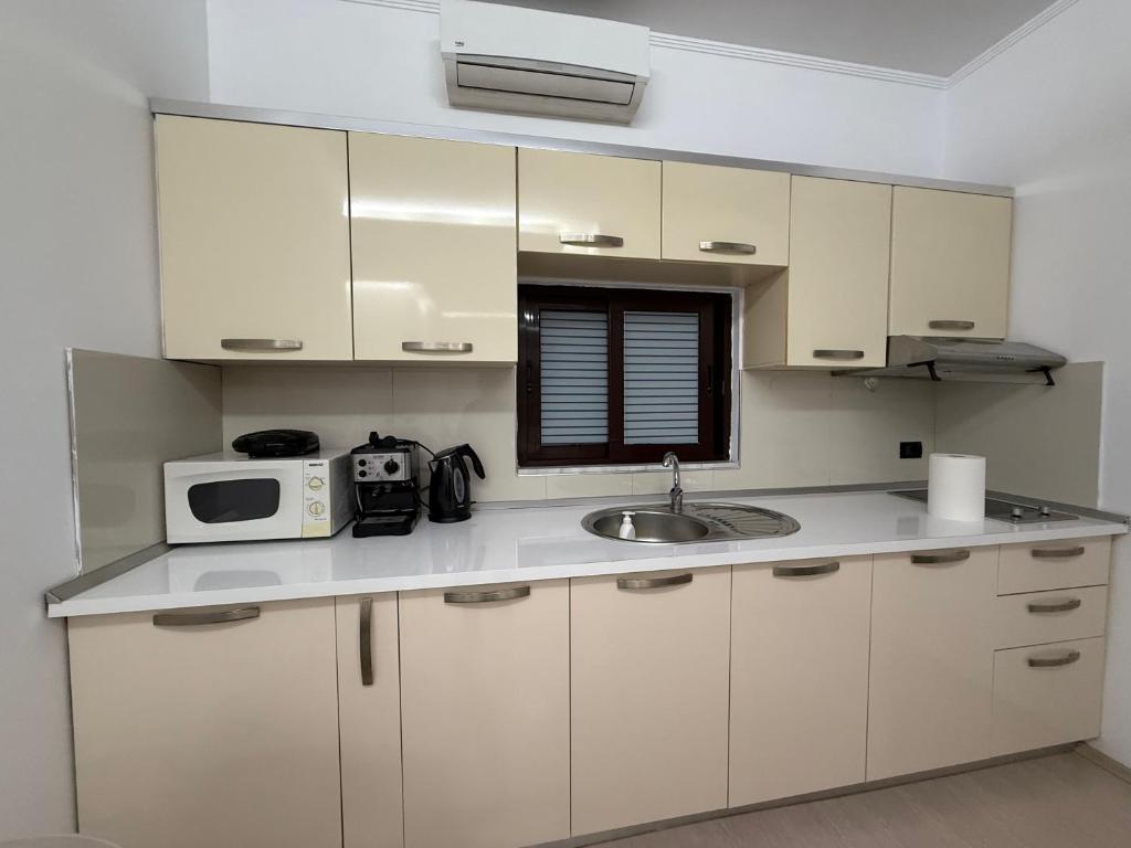 a white kitchen with a microwave and a sink at Ani Apartment with Fireplace in Tirana