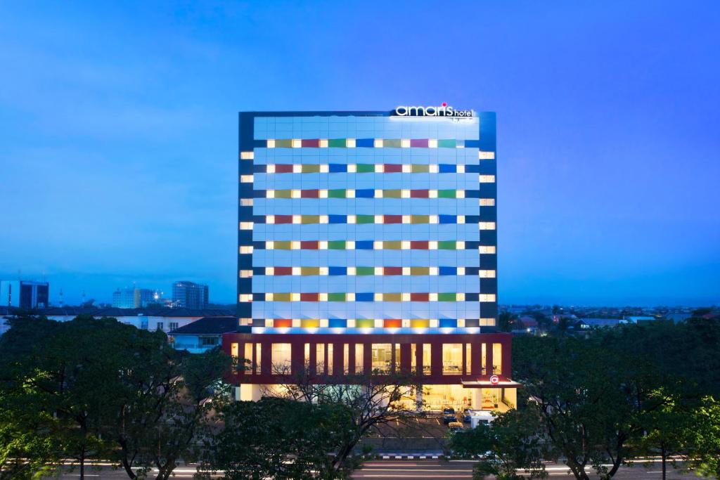 un edificio de hotel iluminado con un cartel en Amaris Hotel Pettarani - Makassar en Makassar