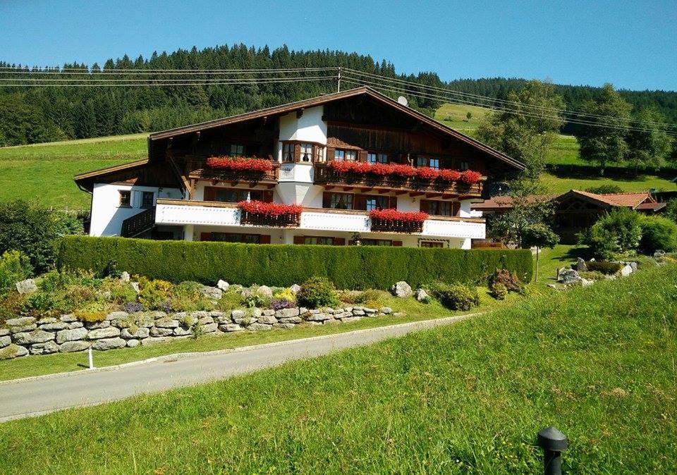 una casa en una colina con una carretera delante de ella en Apartments Haus am Anger - Romantik-Beauty-Wellness, en Jungholz