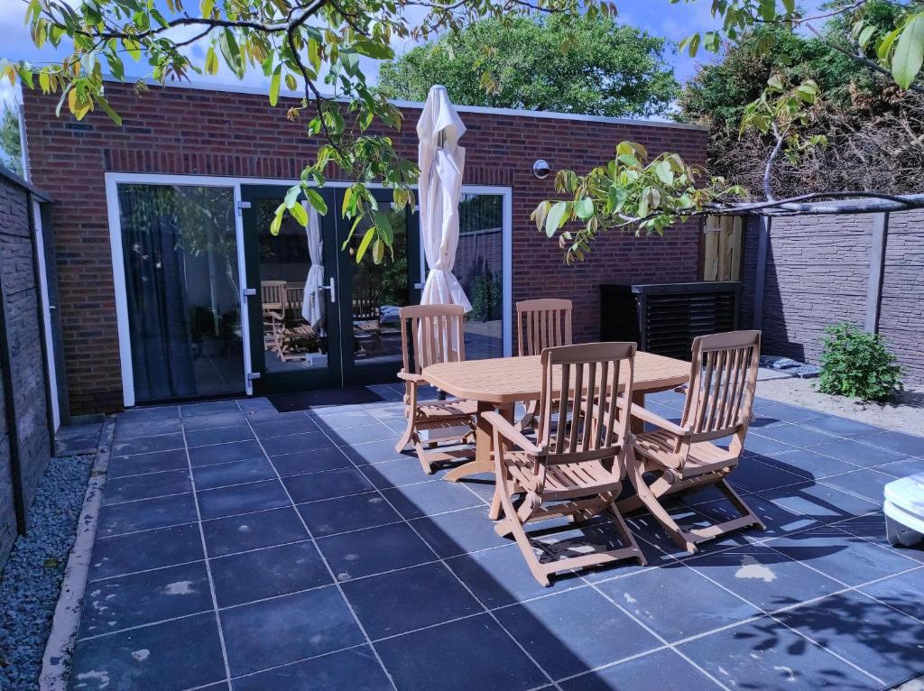 a patio with a wooden table and chairs and an umbrella at Stuivezandeweg 6 in Callantsoog