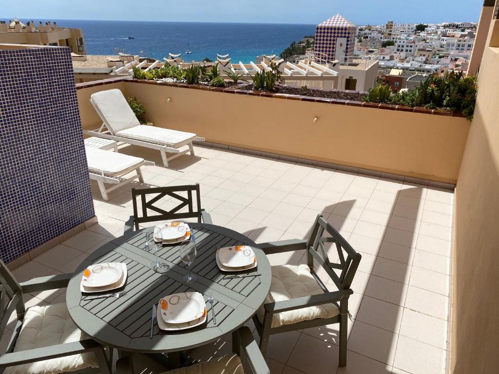 a table and chairs on a balcony with a view of the ocean at Tajinaste Sol in Morro del Jable