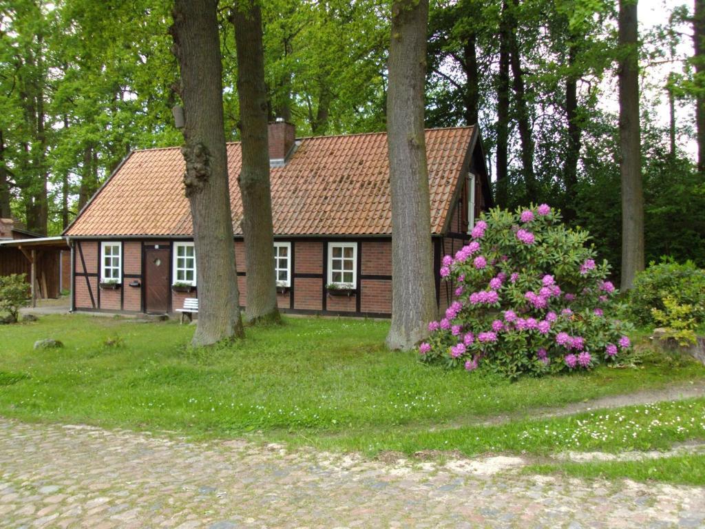 ein Haus mit Bäumen und rosa Blumen davor in der Unterkunft Ferienhaus im Fachwerkstil mit Sauna und Garten in Thomasburg