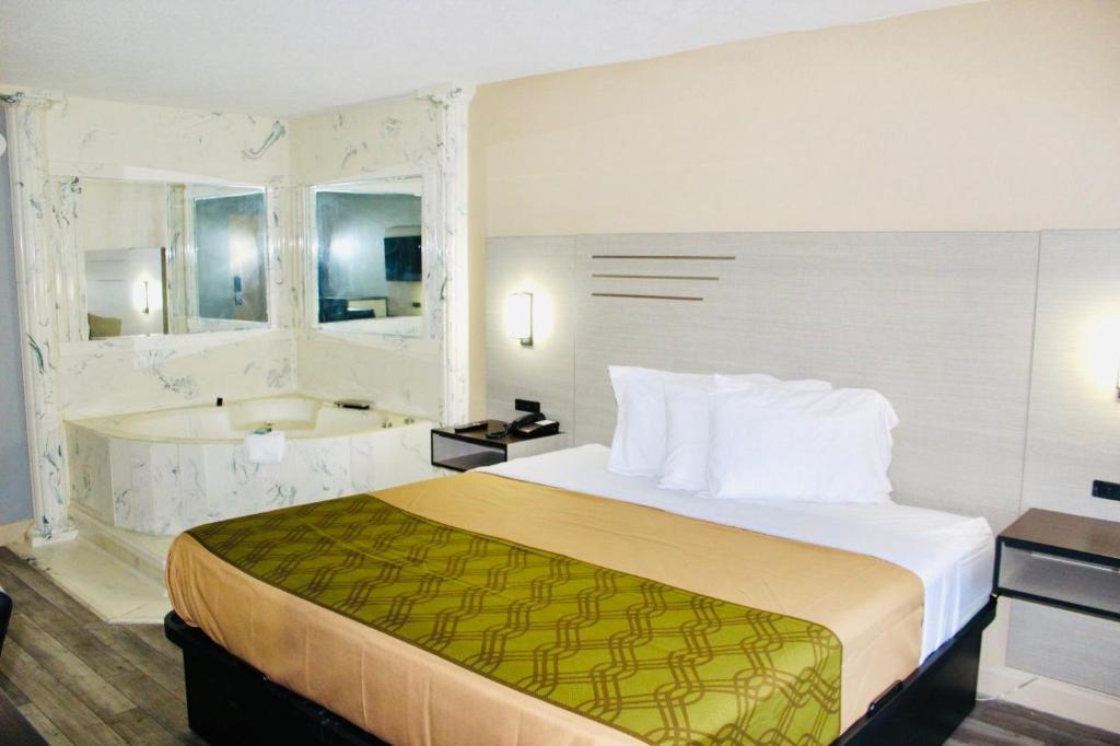 a hotel room with a bed and a bath tub at Milan inn & Suites in Milan