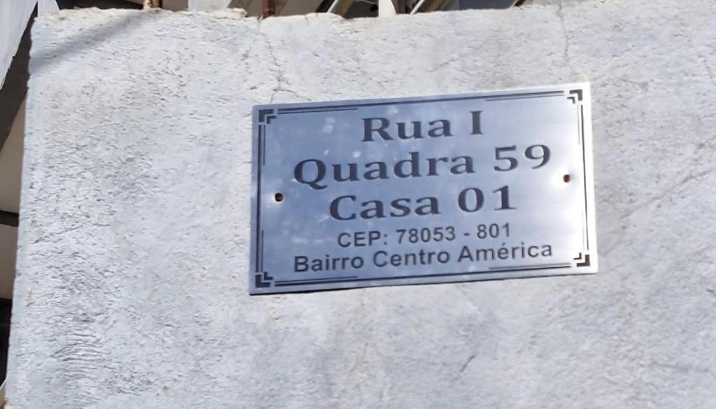 a sign on the side of a white wall at Hospedagem do Elias in Cuiabá