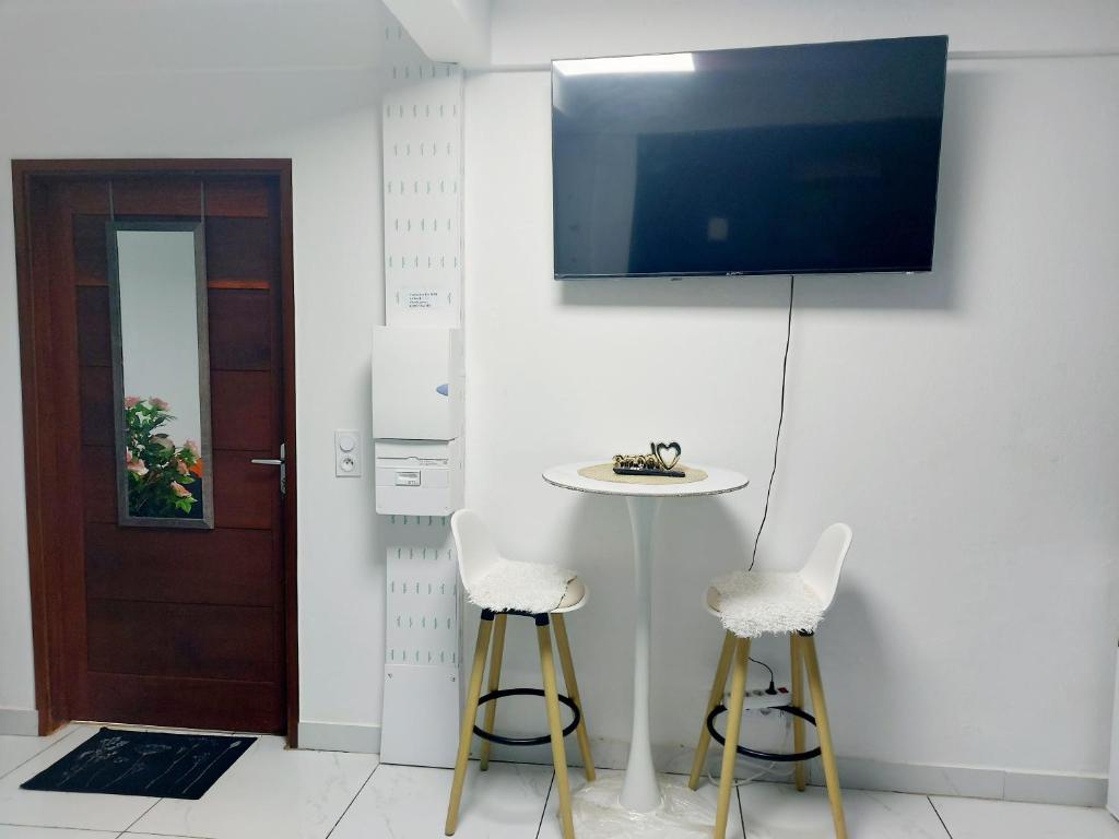 カイエンヌにあるStudio F cosyのテーブルと椅子2脚、壁にテレビが備わる客室です。