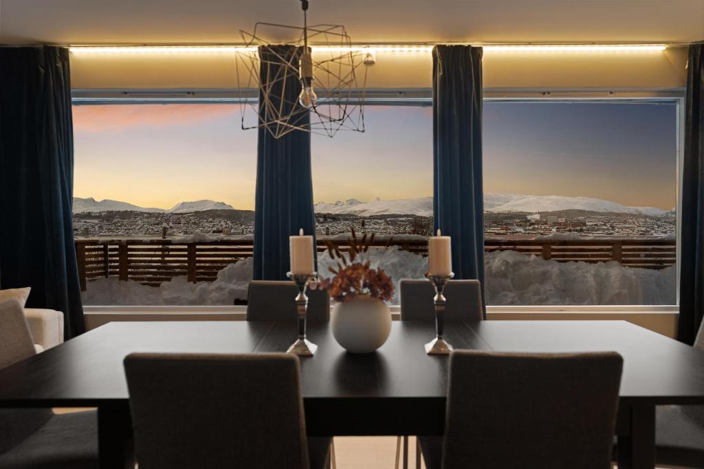 een eetkamer met een tafel en een groot raam bij The Grand Horizon By Paramount in Tromsø