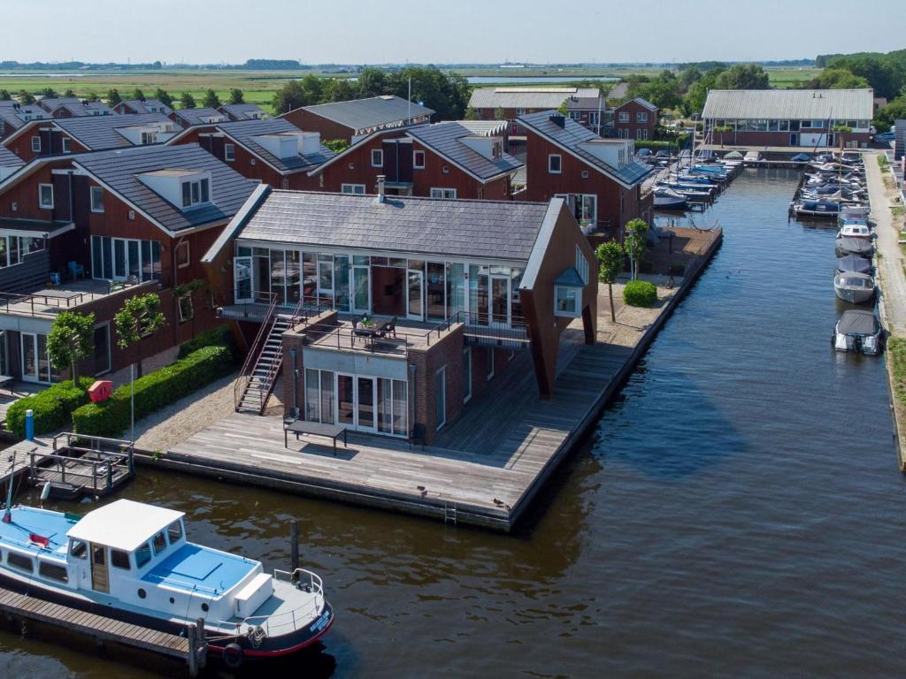 a house on a dock with a boat on the water at Penthouse in Uitgeest