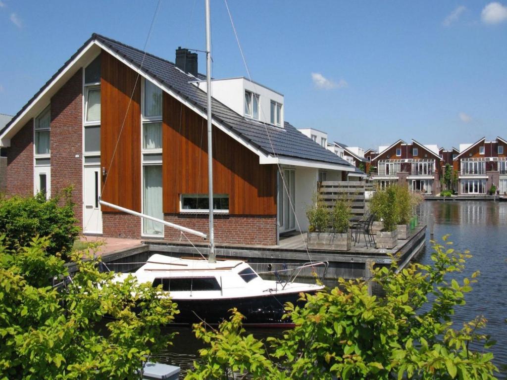 a boat is docked next to a house at Busch en Dam in Uitgeest