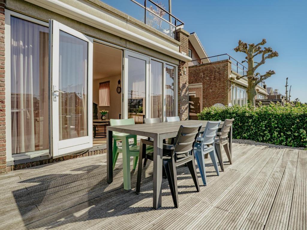 een terras met een tafel en stoelen op een dek bij Westergeest in Uitgeest