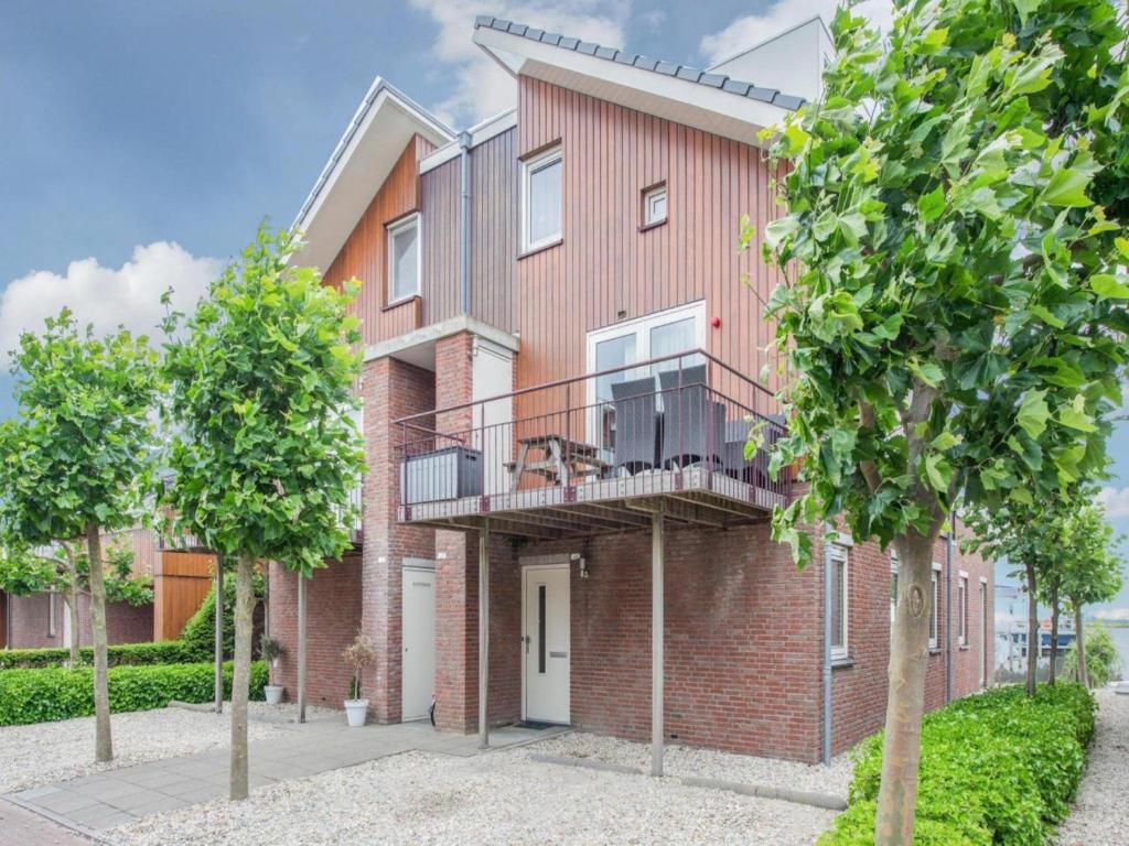 a brick apartment building with a balcony and trees at Waterbase in Uitgeest