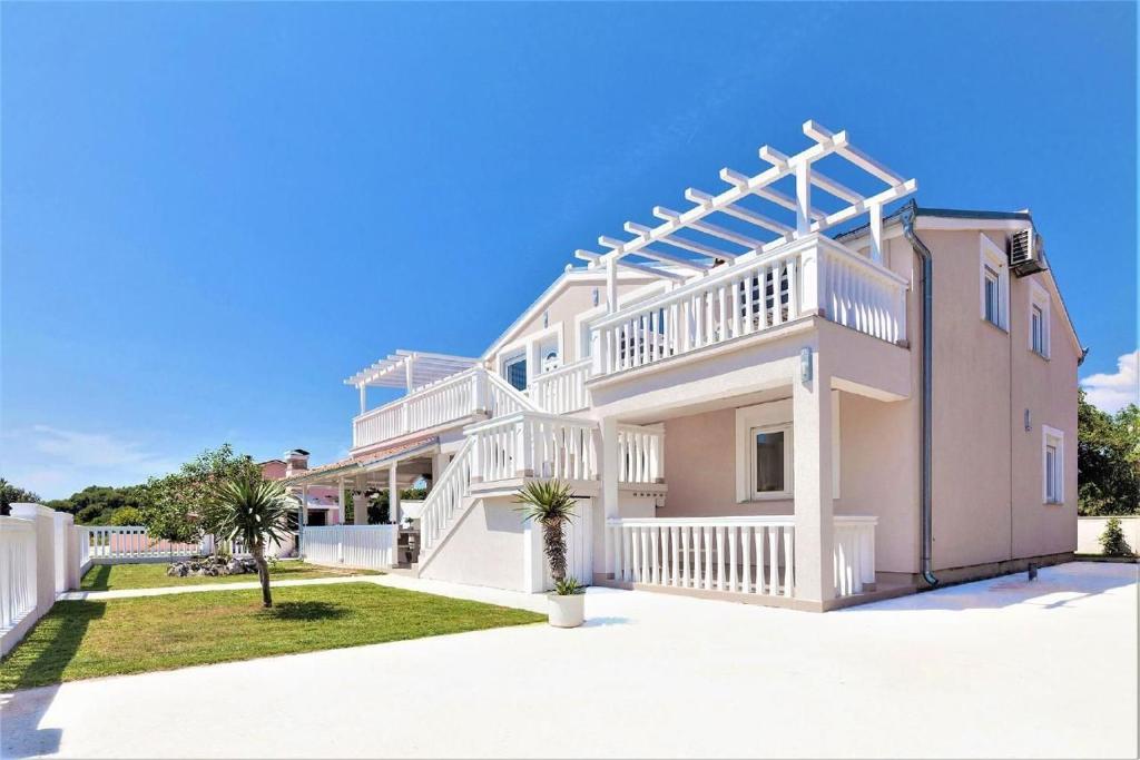 ein großes rosa Haus mit einem weißen Geländer in der Unterkunft Moderne Ferienwohnung mit jacuzzi in Ližnjan