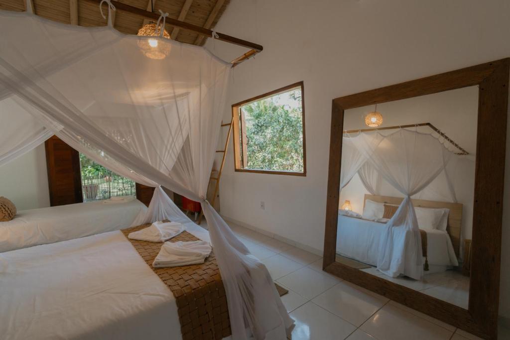 une chambre avec deux lits et un grand miroir dans l'établissement Villa Cacau - Floresta, à Trancoso