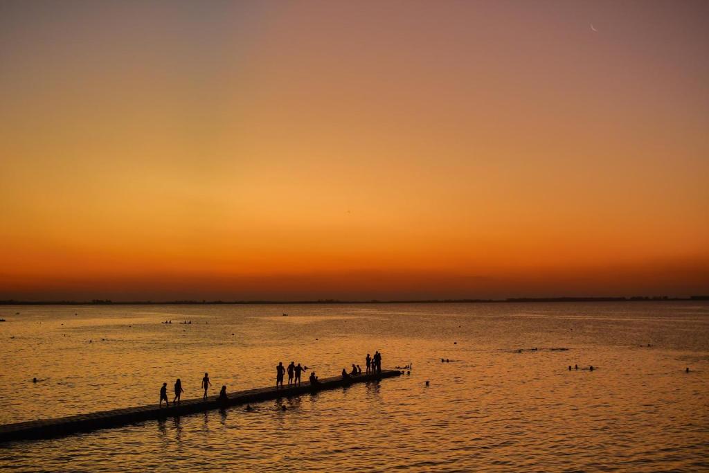 eine Gruppe von Menschen, die auf einem Pier im Wasser stehen in der Unterkunft Amplio departamento con 2 habitaciones- Balcón hacia la pileta y estacionamiento in Miramar